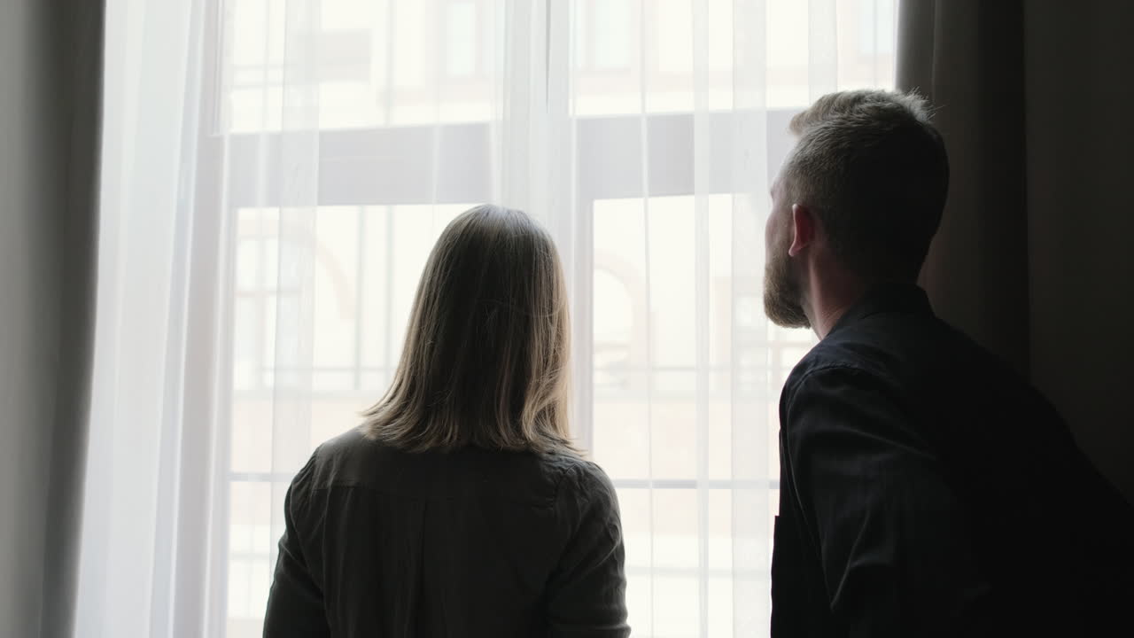 Una pareja mirando por la ventana.