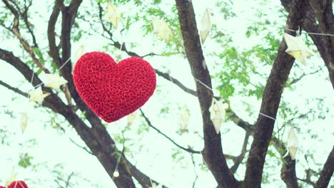 red hearts hanging on a tree with many paper stars and lights twinkling at night. valentine's day concept