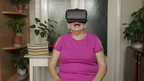 senior grandmother woman in virtual headset glasses watching 3d video in 360 vr helmet at home