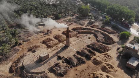 Luftaufnahme-Eines-Rauchigen-Schornsteins,-Der-Stoppeln-Auf-Einer-Farm-In-Khairpur-Sindh-Brennt