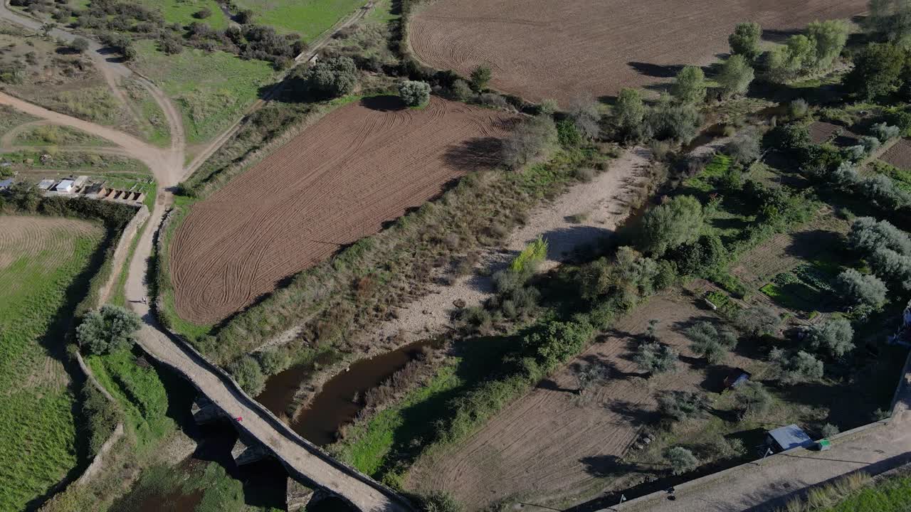 drone gira sobre un antiguo puente romano y las tierras de cultivo circundantes