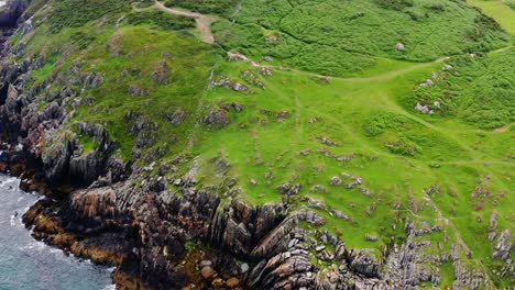 overhead orbit of clogherhead cliff rocks with greywacke terrain and calm sea waves during an irish summer