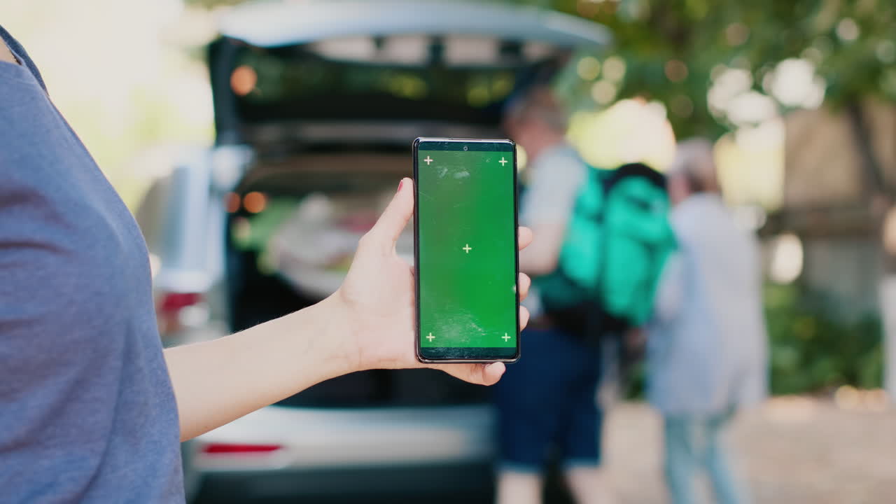 Car trunk with vacation supplies and a smartphone with a green screen