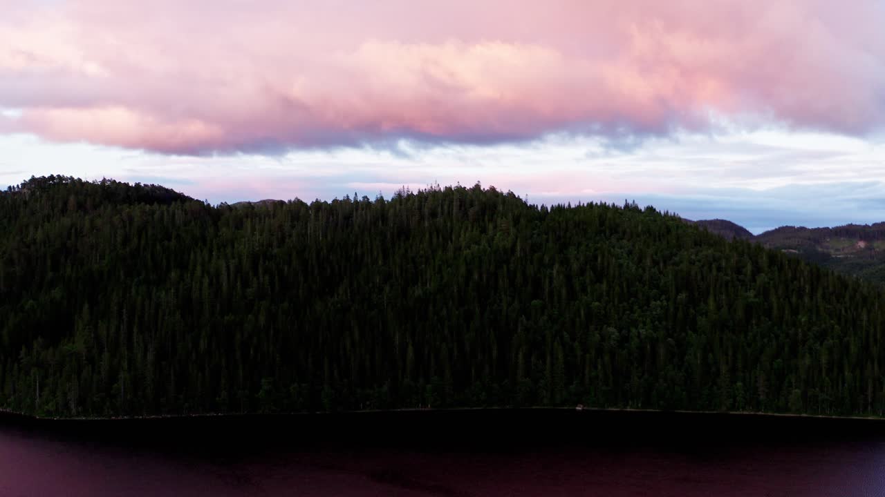 cloudscape sobre exuberantes montañas boscosas junto al tranquilo lago en noruega