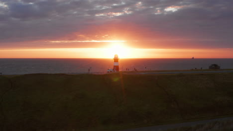 the lighthouse of westkapelle during a bright orange sunset, with a lot of wind