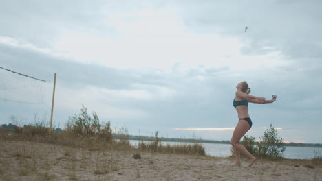 Una-Joven-Jugadora-De-Voleibol-Está-Entrenando-Un-Saque-De-Pelota-En-Una-Cancha-De-Playa-Abierta,-Deporte-De-Equipo,-Un-Jugador-En-Entrenamiento.