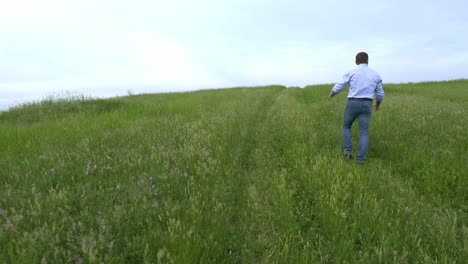 man walking through a green field