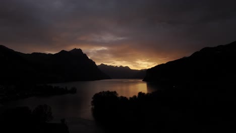 cloudy twilight sky over walensee with mountains in silhouette in switzerland. drone pullback shot