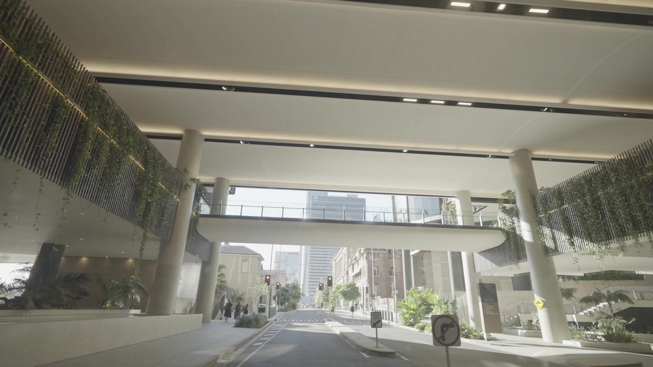 Una moderna pasarela elevada, bordeada de vegetación colgante, atraviesa una calle vacía de la ciudad en Brisbane, bajo el Star Casino.