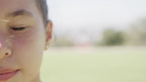 half portrait of happy biracial elementary schoolgirl outdoors in sun, copy space, slow motion