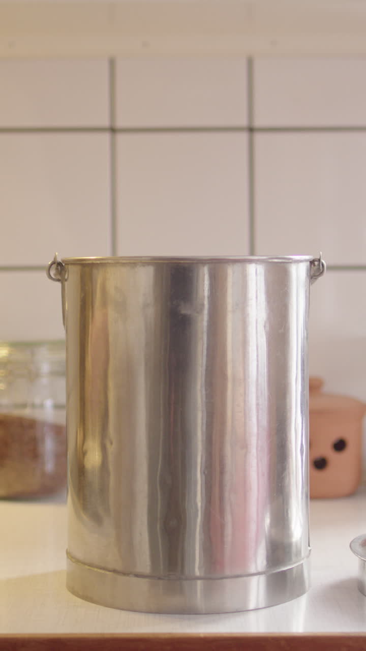 mujer descarta verduras caducadas en un contenedor de compost de acero inoxidable, vertical