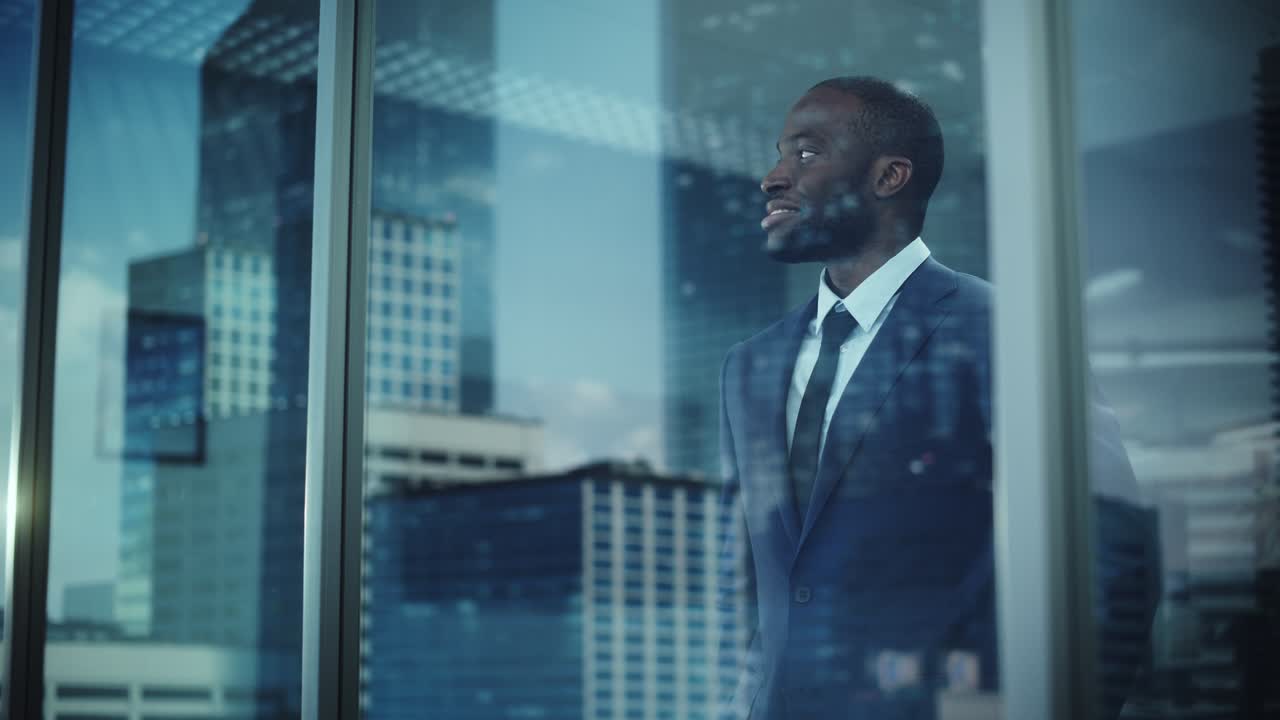 ritratto di un sorridente uomo d'affari afroamericano in abito in piedi nel suo ufficio e guardando fuori dalla finestra la grande città. un investitore di e-commerce di successo che lavora sodo per essere in cima.