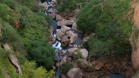 overhead view looking down at valley with river running through large boulders in ronda