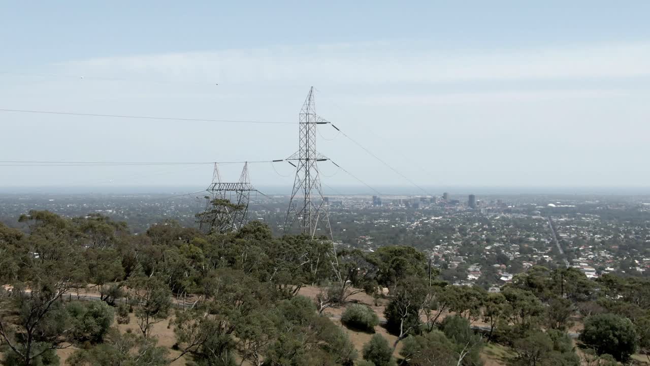 Transmission Tower In Dense Trees With City Landscape Of Adelaide At Backdrop In Australia