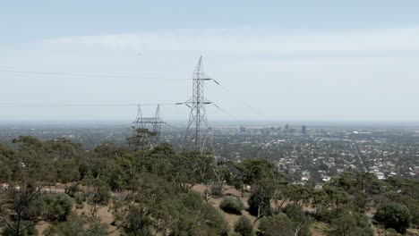 transmission tower in dense trees with city landscape of adelaide at backdrop in australia