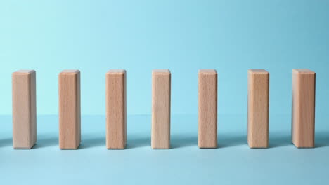 domino effect, row of wooden domino falling down with blue background