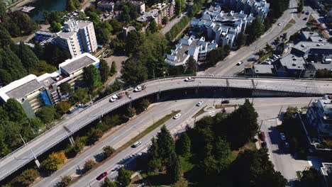 Luftaufnahme-über-Der-Überführung-Leichter-Verkehr-Auf-Allen-Fahrspuren-Während-Der-Hauptverkehrszeit-Vogelperspektive-Niedrige-Häuser-Hohe-Bäume-Leere-Brücke-Verkehr-Sandlastwagen-Vorbeifahrend-Mit-Baufahrzeugen,-Die-Auf-Dem-Seitenstreifen-4-5-Geparkt-Sind