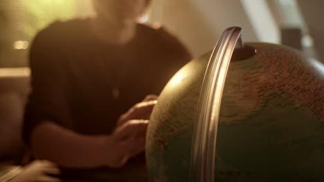 person examining a globe in warm light