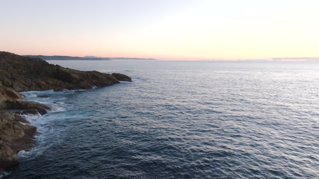 Luftaufnahme: Drohne fliegt bei Sonnenaufgang um die Landzunge von Tathra, um den Tathra Pier an der Südküste von NSW, Australien, zu enthüllen.