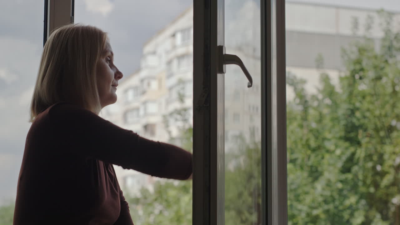 una mujer lava una ventana en el apartamento de un edificio alto 2