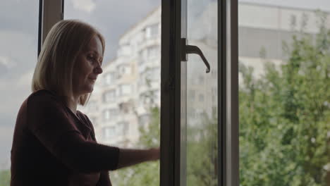 a woman washes a window in the apartment of a high-rise building 2