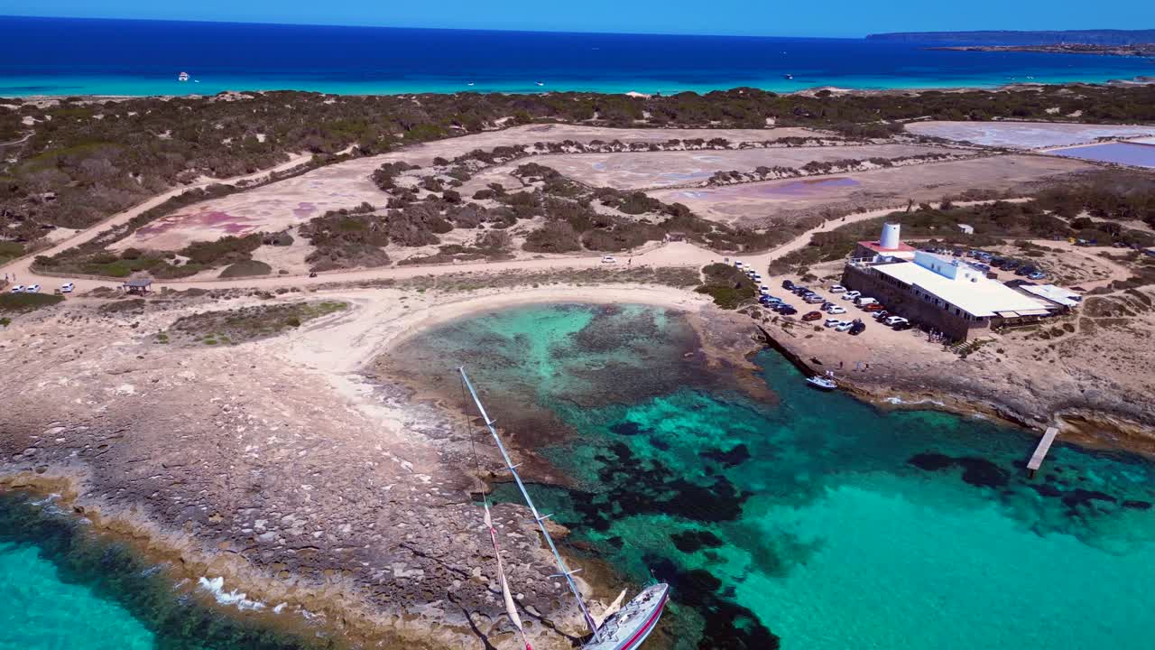 Sailboat stranded on cliff near the coast of Formentera Island, Spain, during a summer sunny day. Brilliant aerial view flight tilt up drone