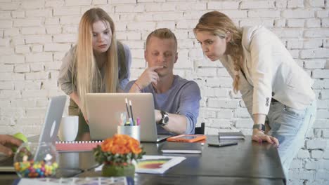 business colleagues discussing something on laptop in the office. coworkers partnership in common business. an employee man helps two women colleagues with project