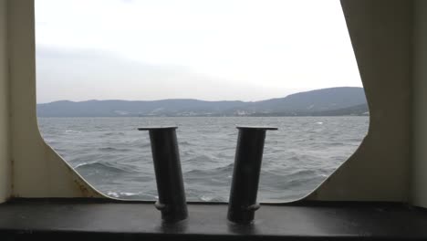 View-To-Ocean-Through-Ferry-Boat-Window-With-Bollards-And-Mountains,-Tasmania,-Australia