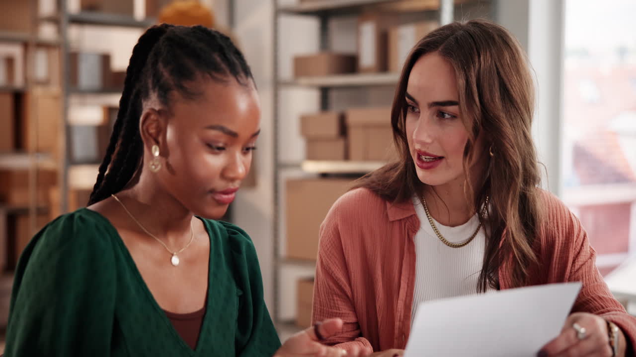 Two Diverse Businesswomen Discussing Paperwork in a Modern Office