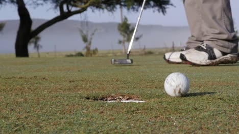 golfer putting towards hole and misses, point of view from hole, slow motion