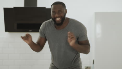 happy black man dancing at open kitchen. young guy making dance at home.