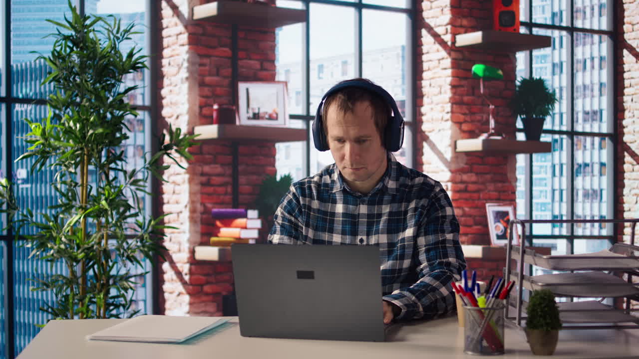 Lavoratore che scrive su carta, prende appunti e ascolta musica dal portatile.