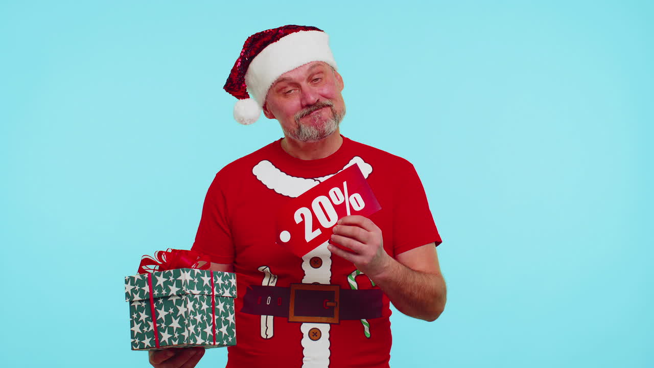 hombre con camiseta roja de navidad mostrando caja de regalos y inscripciones de descuento del 20 por ciento nota de texto de banner