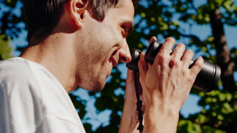 man taking photos and using binoculars in a park