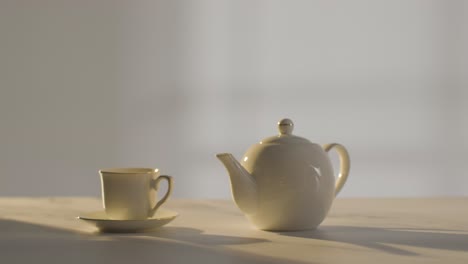 foto de estudio de una persona haciendo y vertiendo una taza tradicional británica de té usando una tetera