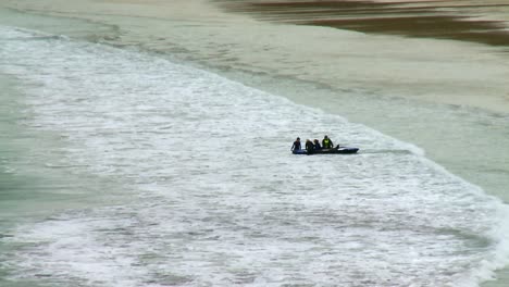 A-group-of-people-taking-a-kayak-through-the-surf-on-a-beach-on-the-Isle-of-Harris,-part-of-the-Outer-Hebrides-of-Scotland