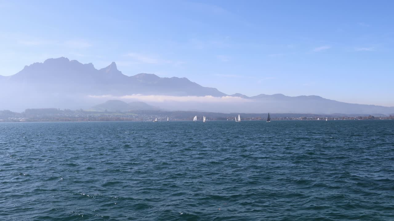 Sailboats sailing on the lake with mountains in the background, Thun lake Switzerland