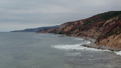 top down birds eye aerial view of the waves crashing on a rocky southern california beach