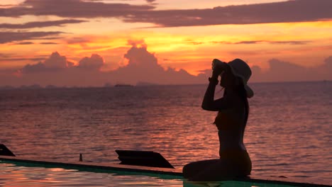 silhouette of woman sitting by the poolside with twilight background