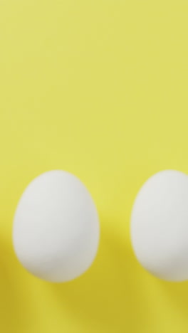 video of row of one brown and four white eggs with copy space on yellow background