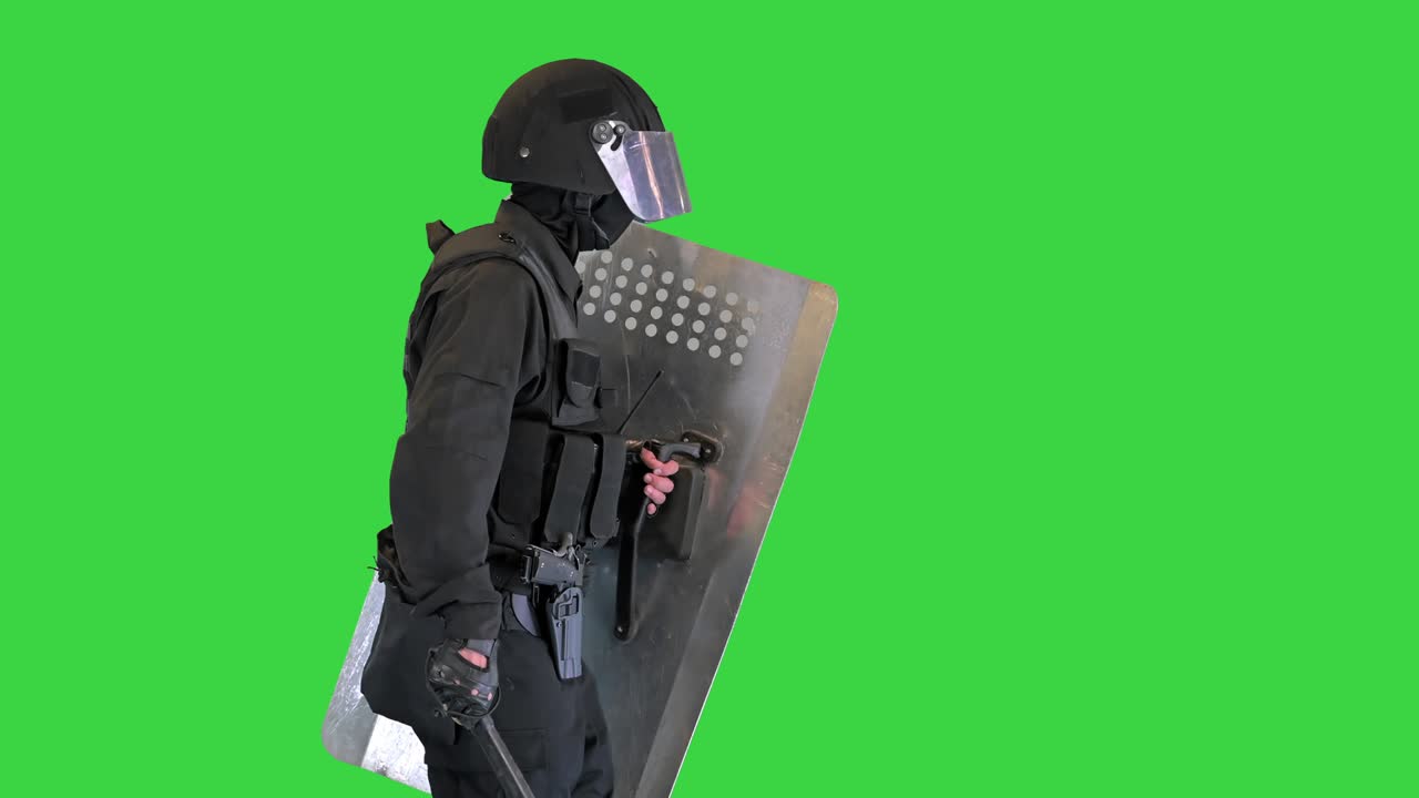 Heavily armored policeman with a shield and a baton walking on a Green Screen, Chroma Key