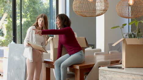 unpacking boxes, lesbian couple discussing home decor in modern living room