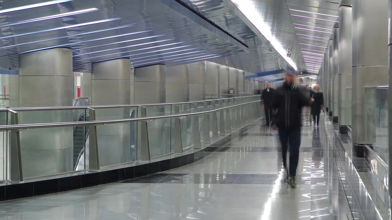 Interior de uma estação de metrô moderna com timelapse de corredor de transferência. Pessoas caminhando em uma passagem entre estações. Reflexos no chão