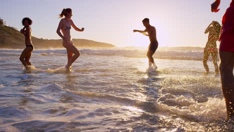 amigos jugando en el océano al atardecer