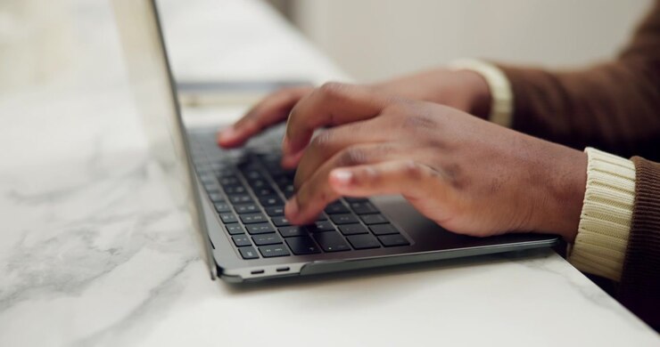 Persona che digita sulla tastiera del laptop su una scrivania in marmo