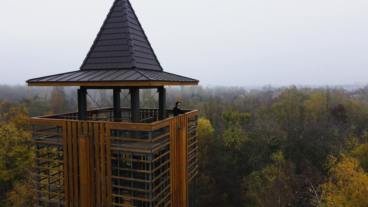 hombre de pie en la torre de observación por encima del arboreto forestal, fundador