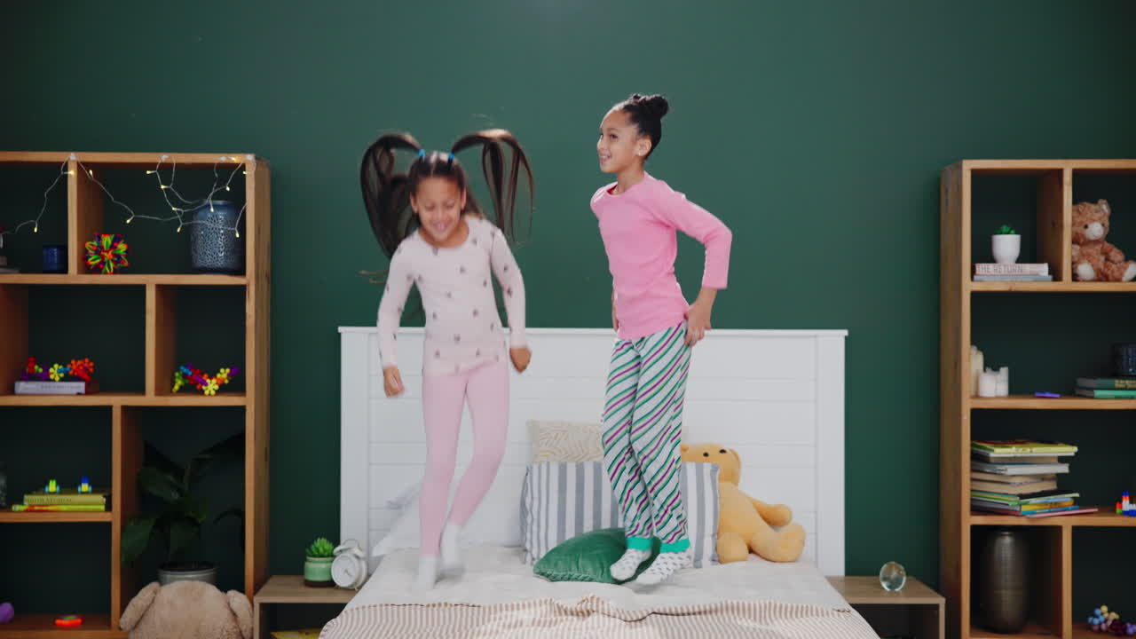 Two Girls Jumping on Bed in Pajamas