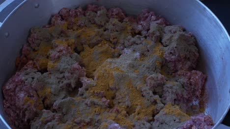 curry powder being added to large pan full of mince meat by spoon