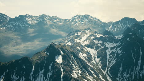 Antena-Sobre-El-Valle-Con-Montañas-Cubiertas-De-Nieve-En-La-Distancia