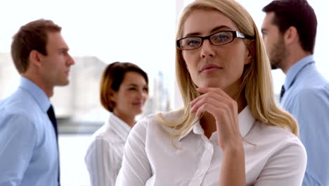 businesswoman looking at camera with colleagues behind her